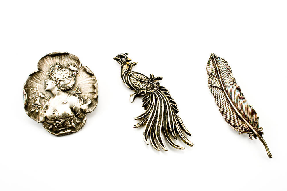 Three antique silver brooches isolated on white